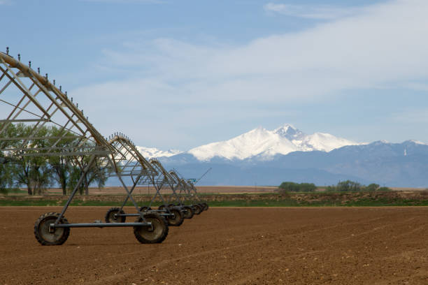 A Pivot Irrigation System in a farming field with Longs Peak Mountain in the background on a sunny day